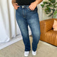 Woman wearing RFM Full Size High Rise Straight Tummy Control Jeans in a living room setting, displaying the jeans' flattering high-waist and straight-leg cut.