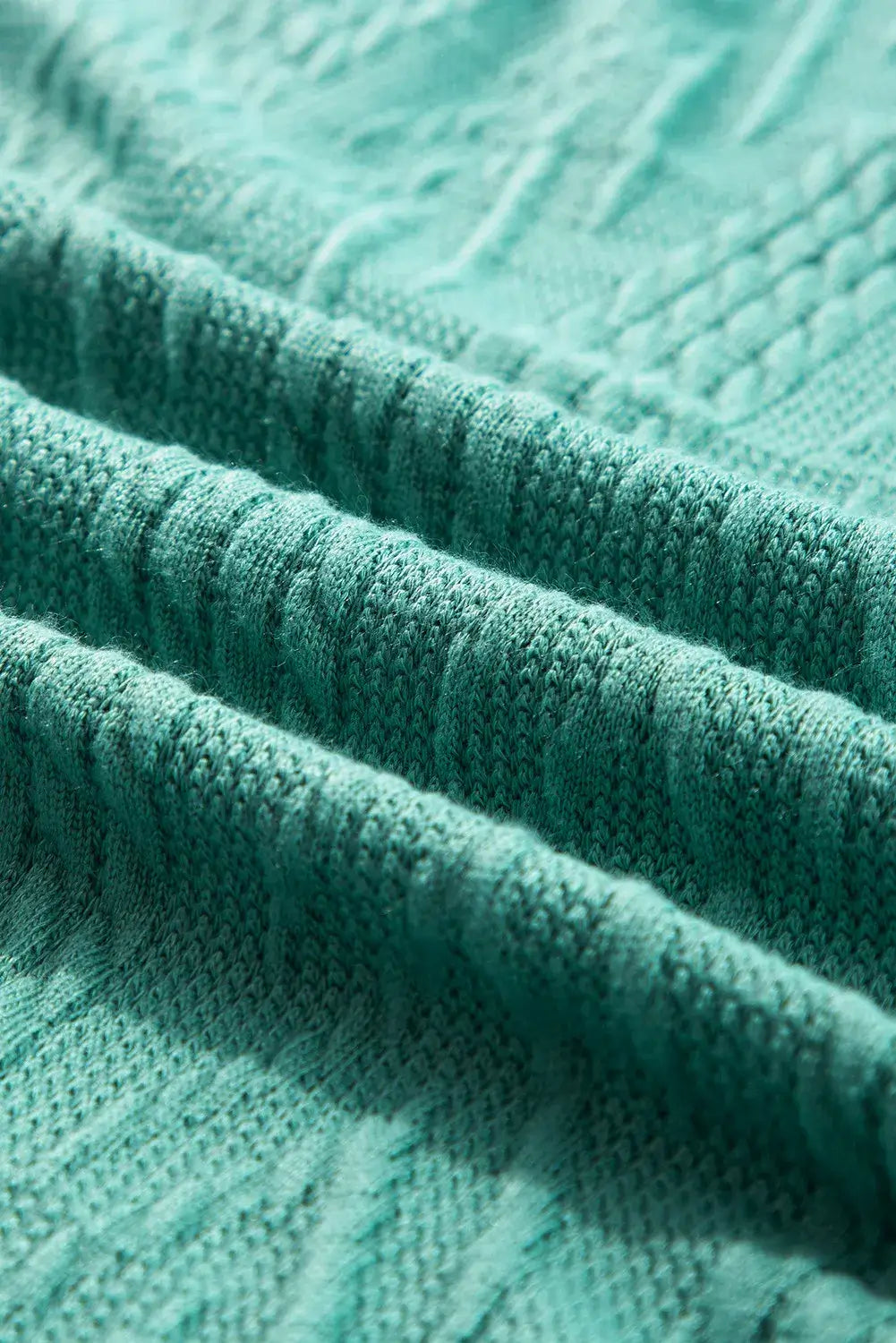 Close-up of mint green textured fabric showing intricate patterns and slight stretch. Made from 97% polyester and 3% elastane.