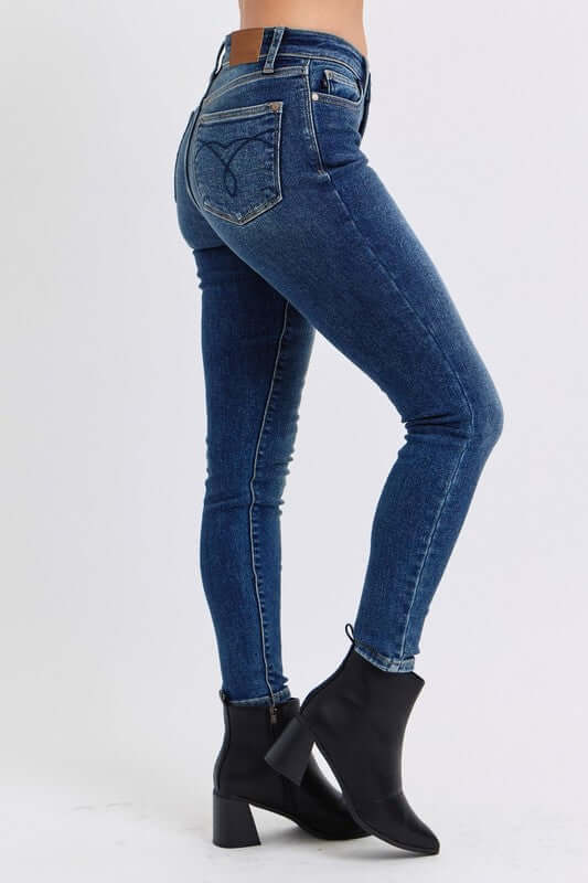 Judy Blue mid-rise waist skinny jeans in dark blue with pockets, styled with black ankle boots. Perfect for any occasion!