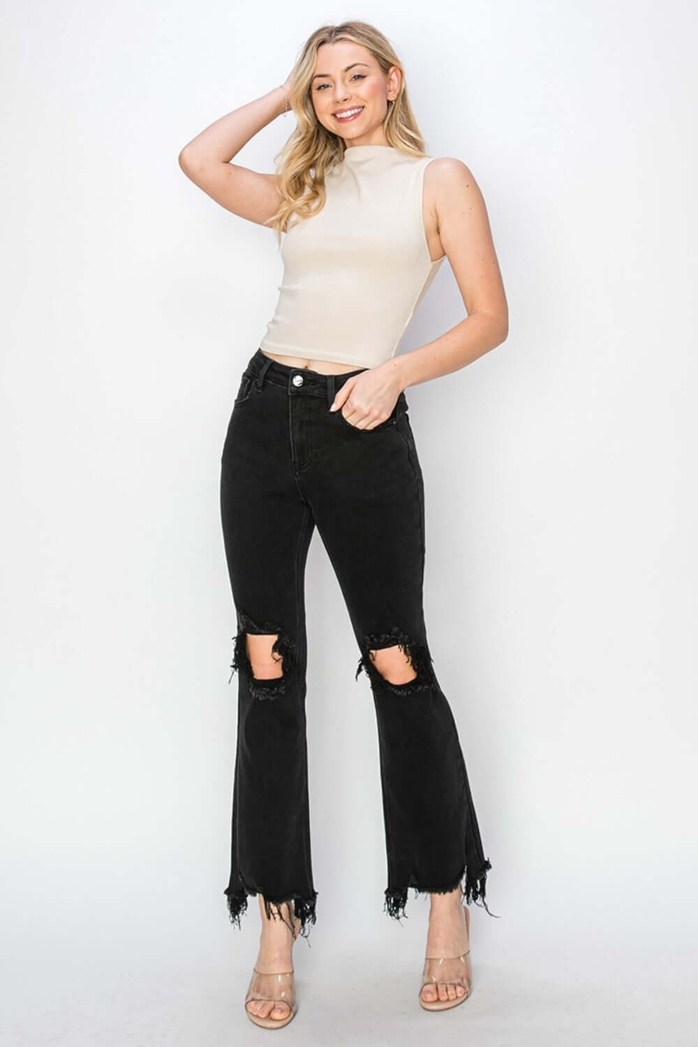 Woman modeling stylish Risen Jeans with distressed raw hem and ripped design, featuring convenient pockets and unique original cuff style.