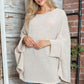 Woman wearing Bella Road Round Neck Batwing Sleeve Sweater in a cozy setting.