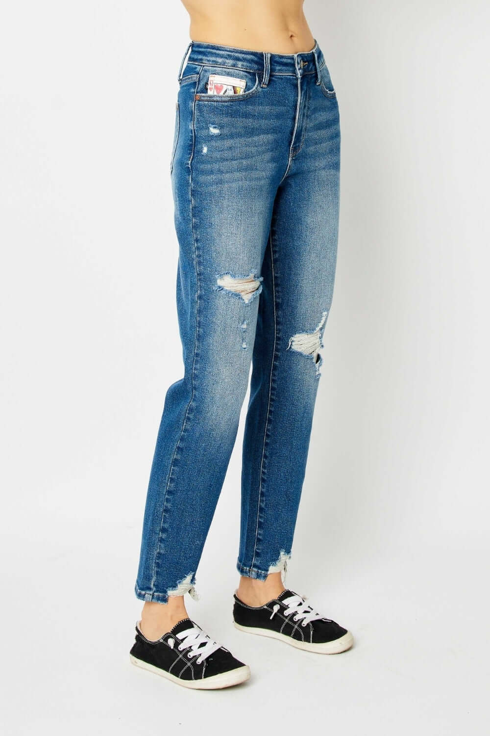 Woman wearing distressed slim Judy Blue Jeans with a trendy ripped design, paired with black sneakers for a casual look.