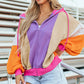 Woman wearing drawstring color block zip up long sleeve hoodie in purple, beige, orange, and pink, paired with denim shorts.