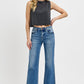 Trendy woman wearing RISEN raw hem ankle bootcut jeans with a stylish crop top and heels, showcasing a chic, casual look.