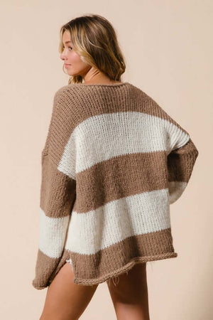 Stylish woman in a brown and white striped oversized sweater, showcasing a relaxed fit and dropped shoulder design.