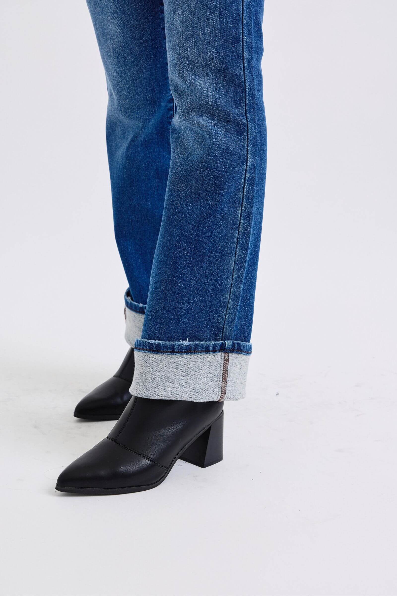 Stylish close-up of mid-rise bootcut jeans with cuffed hems paired with chic black heeled boots. Perfect for any outfit!