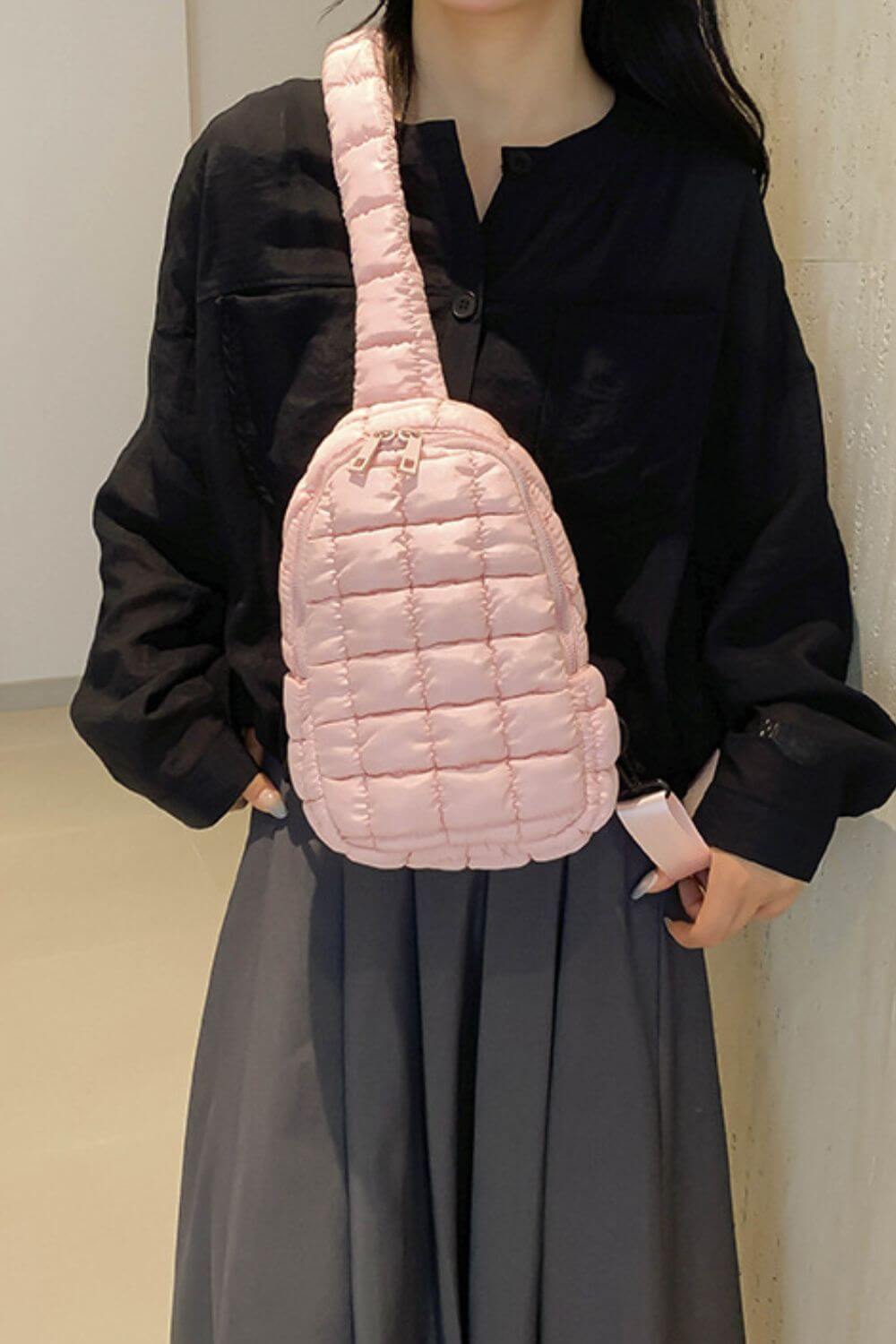 Woman wearing Bella Road Quilted Nylon Crossbody Bag in pink, styled with a black top and gray skirt, showcasing chic fashion.