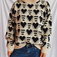 Woman wearing Bella Road Heart Contrast Long Sleeve Dropped Shoulder Sweater with heart pattern and blue jeans