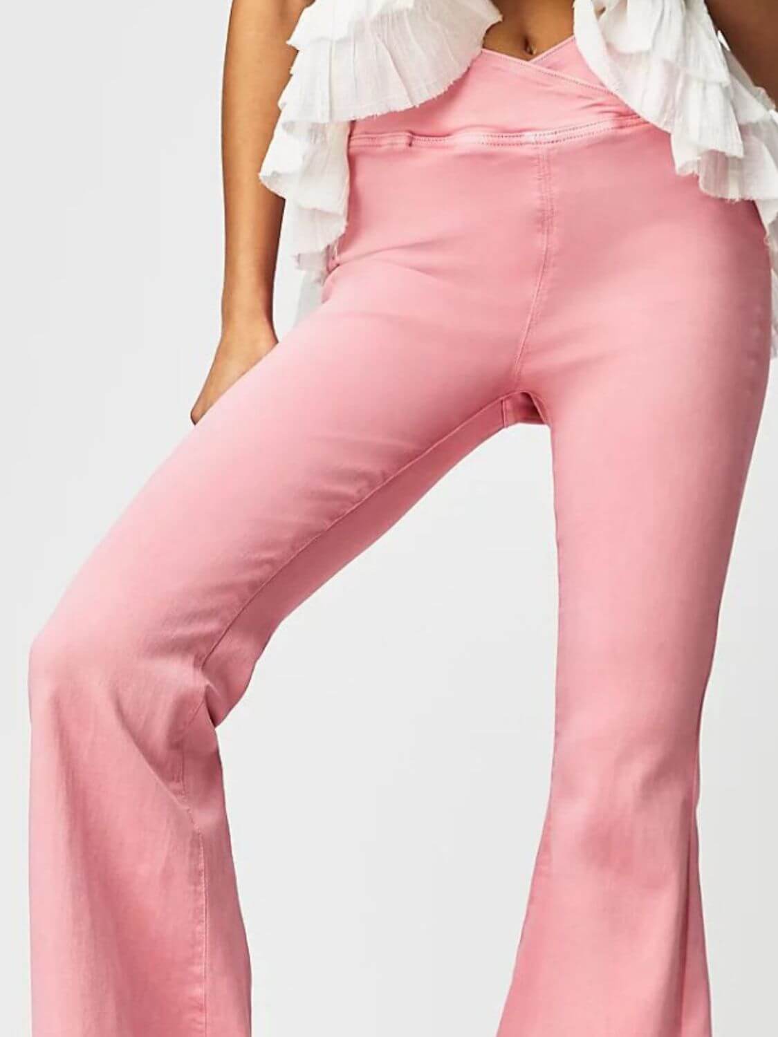 Woman wearing pink Asymmetric Waist Flare Jeans with a white ruffled top, showcasing unique waistline design.