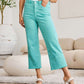 Woman wearing Crop Chloe Full Size Tummy Control High Waist Raw Hem Jeans in teal paired with a white tank top and sandals