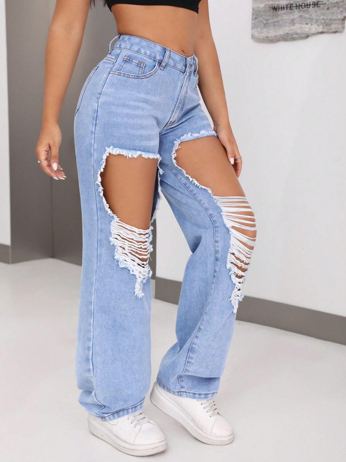 Woman wearing distressed jeans with large rips above the knees, showcasing a trendy fashion look. No-stretch material, 85% cotton, 15% polyester.