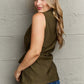 Woman wearing Follow The Light Sleeveless Collared Button Down Top in olive green, paired with jeans, posing against a textured wall.