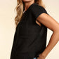 Woman wearing a black pocketed round neck cap sleeve knit top with jeans, showcasing a relaxed and comfortable spring-summer look.