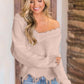 Woman wearing Bella Road frayed hem dropped shoulder sweater in cozy indoor setting.