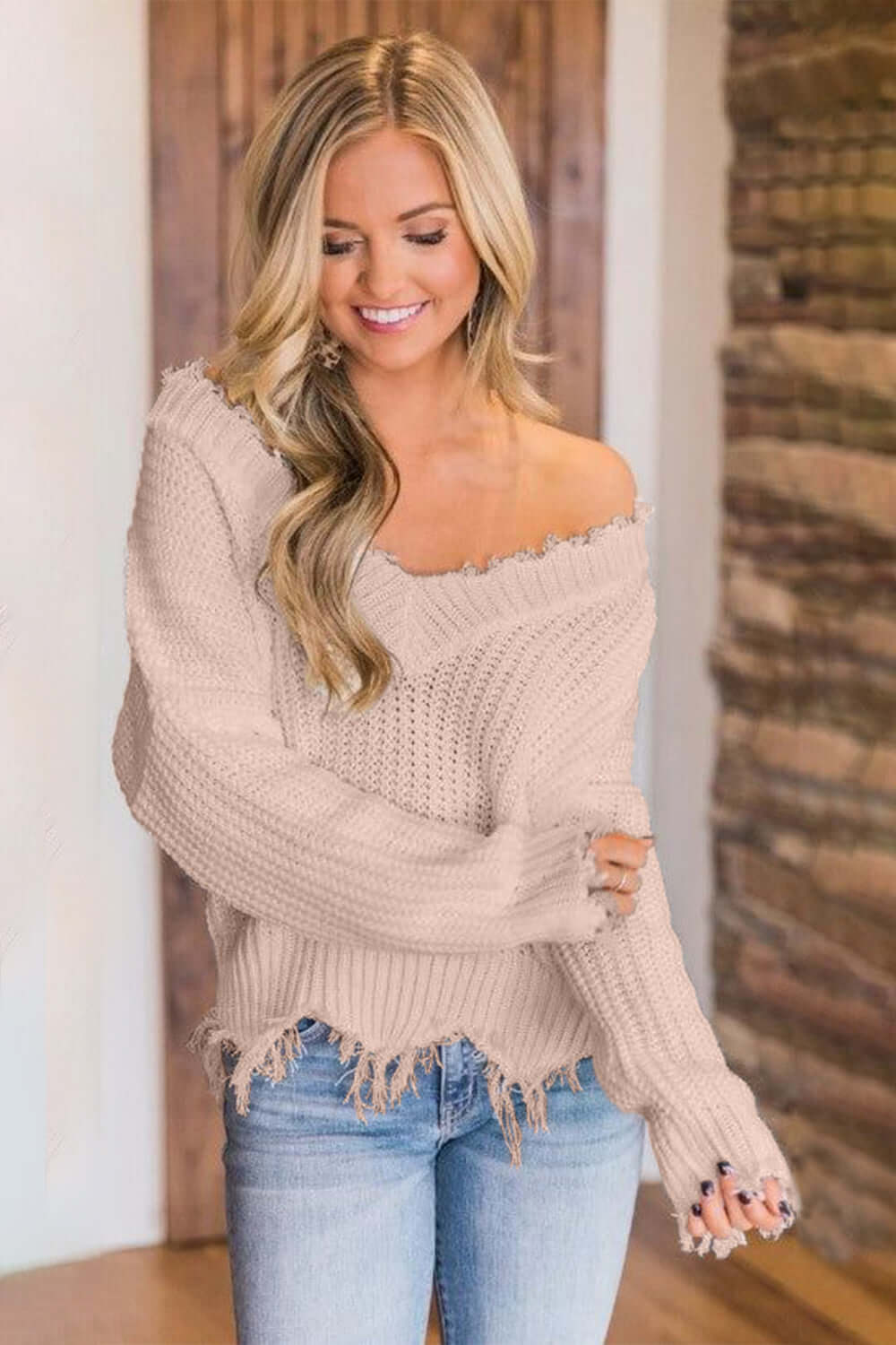 Woman wearing Bella Road frayed hem dropped shoulder sweater in cozy indoor setting.