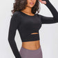 Woman in a black long-sleeved cropped top with cutout detail, showcasing stylish athletic wear perfect for workouts.