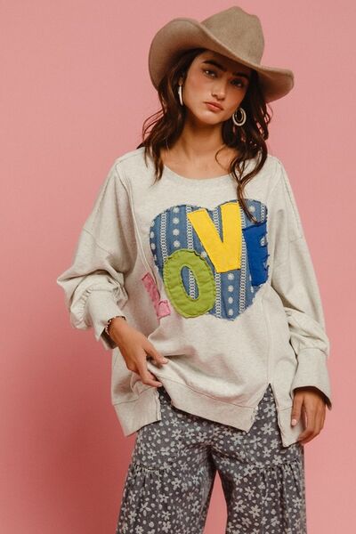 Fashionable woman in LOVE Heart Patch Slit French Terry Sweatshirt with stylish hat and floral pants against pink background.