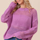 Woman wearing BiBi Openwork Long Sleeve Knit Top in purple, showcasing intricate openwork details and long sleeves, styled with blue jeans.