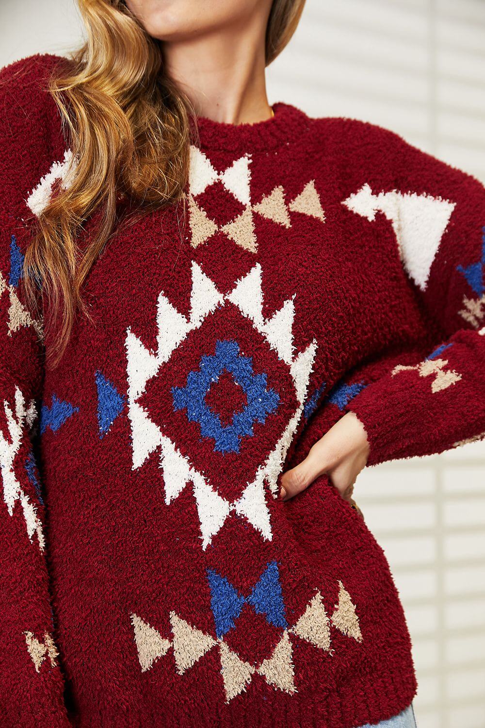 Model wearing a HEYSON Aztec fuzzy sweater with vibrant red, blue, and white geometric patterns, showcasing its cozy texture.