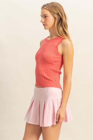 Model showcasing a coral ribbed round neck sweater tank paired with a pink flared skirt.