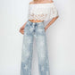 Woman wearing Risen Jeans Full Size Raw Hem Star Wide Leg Jeans with white off-shoulder top, showcasing trendy and fashionable wide-leg denim.