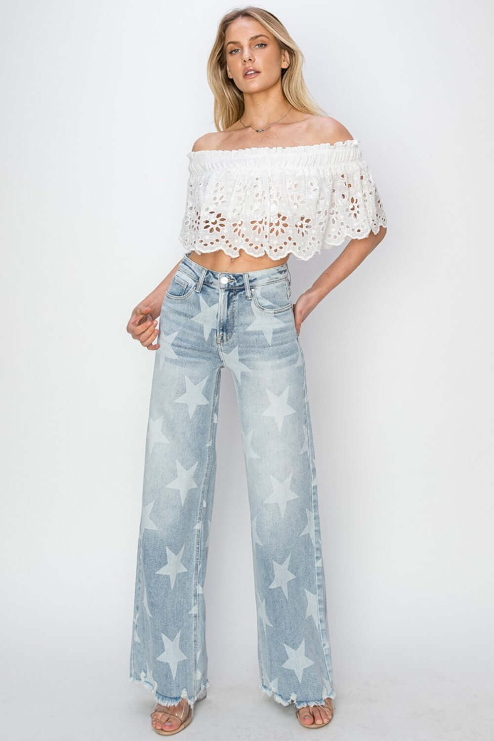 Woman wearing Risen Jeans Full Size Raw Hem Star Wide Leg Jeans with white off-shoulder top, showcasing trendy and fashionable wide-leg denim.