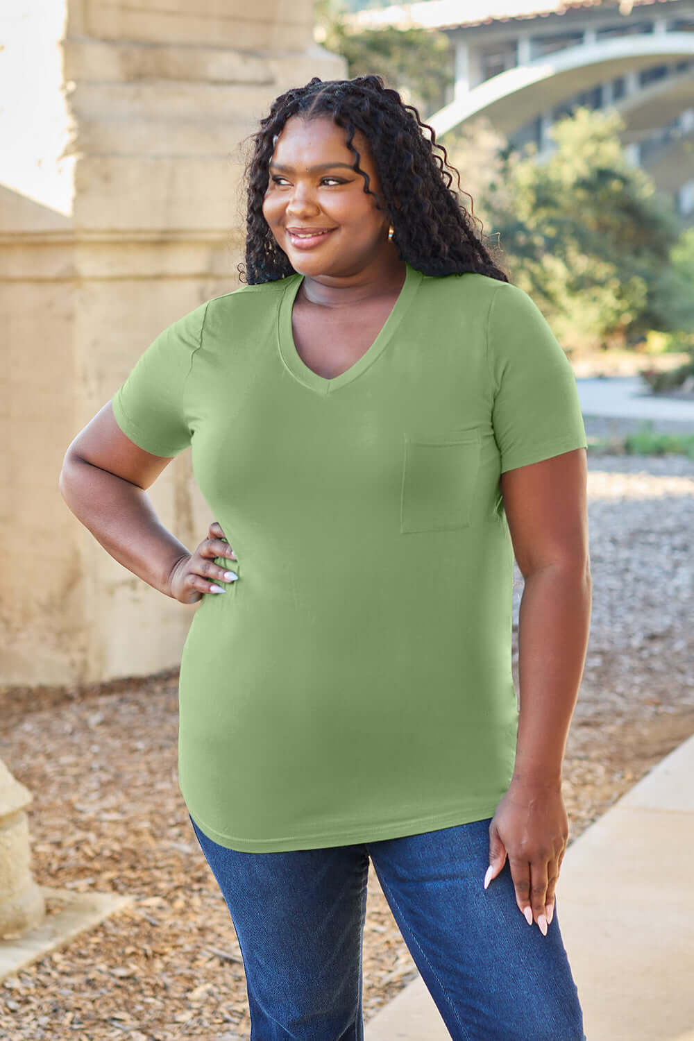 Woman wearing a green Basic Bae Bamboo Full Size V-Neck Short Sleeve T-Shirt outdoors.