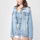 Woman wearing a distressed long sleeve denim jacket over a blue top and white shorts for a casual yet stylish look by Risen Jeans.