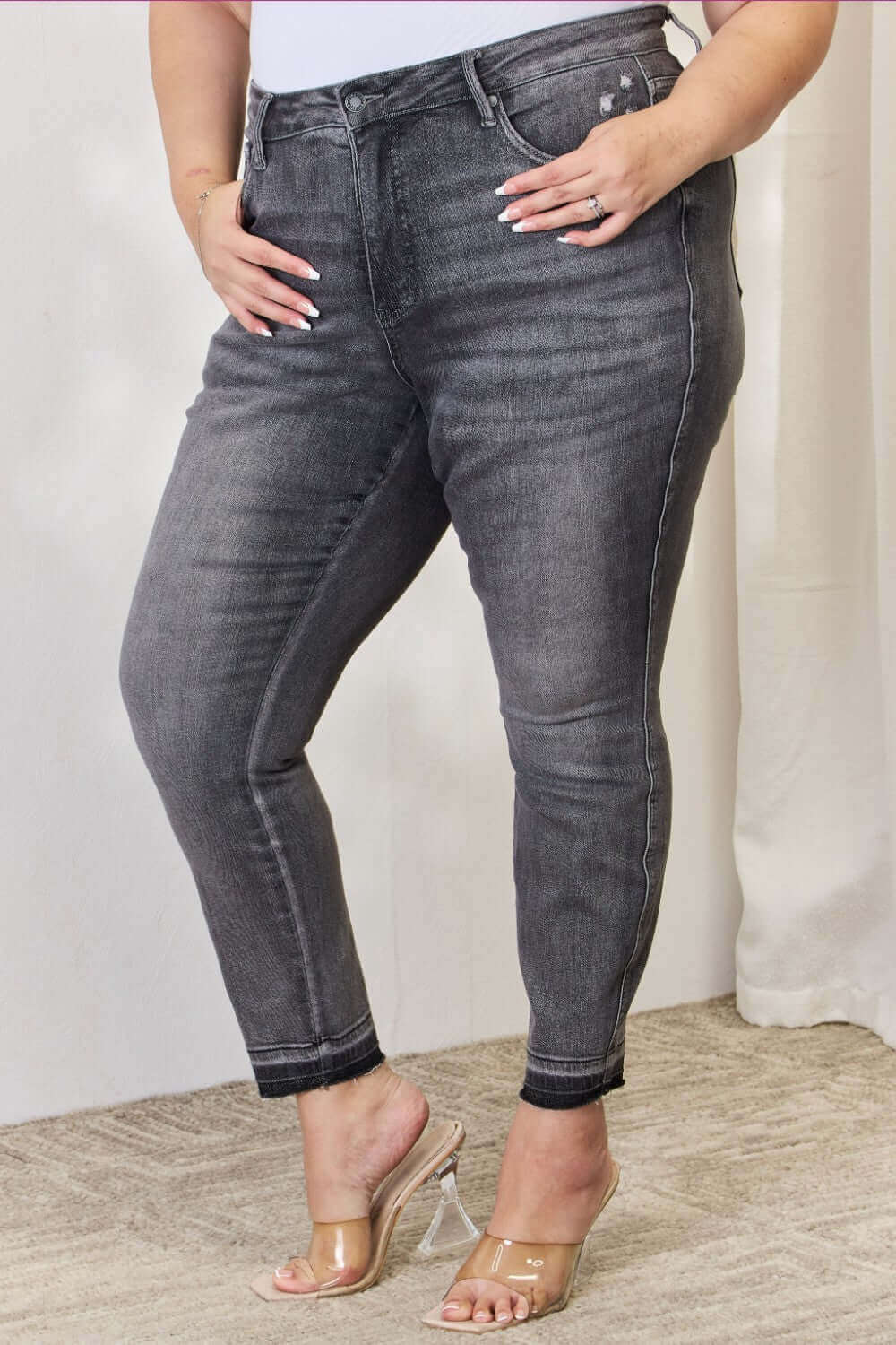 Woman wearing High Waist Tummy Control Release Hem Skinny Jeans in black by Judy Blue Jeans, offering a flattering and comfortable fit.