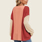 Woman wearing a Double Take Texture Contrast Long Sleeve T-Shirt in red and beige tones, showcasing trendy and stylish layers.