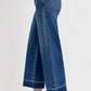 Side view of RISEN tummy control high rise crop wide hem jeans with black platform shoes.