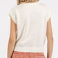 Back view of stylish contrast letter cap sleeve knit top in cream, paired with trendy pants for a casual look.