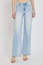 Model wearing RISEN Full Size Wide Leg V Dipped Front Waist Jeans with light blue wash and unique V-shaped waistband.