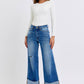 Stylish model wearing Judy Blue distressed high waist wide leg jeans with a fitted white top and heels.