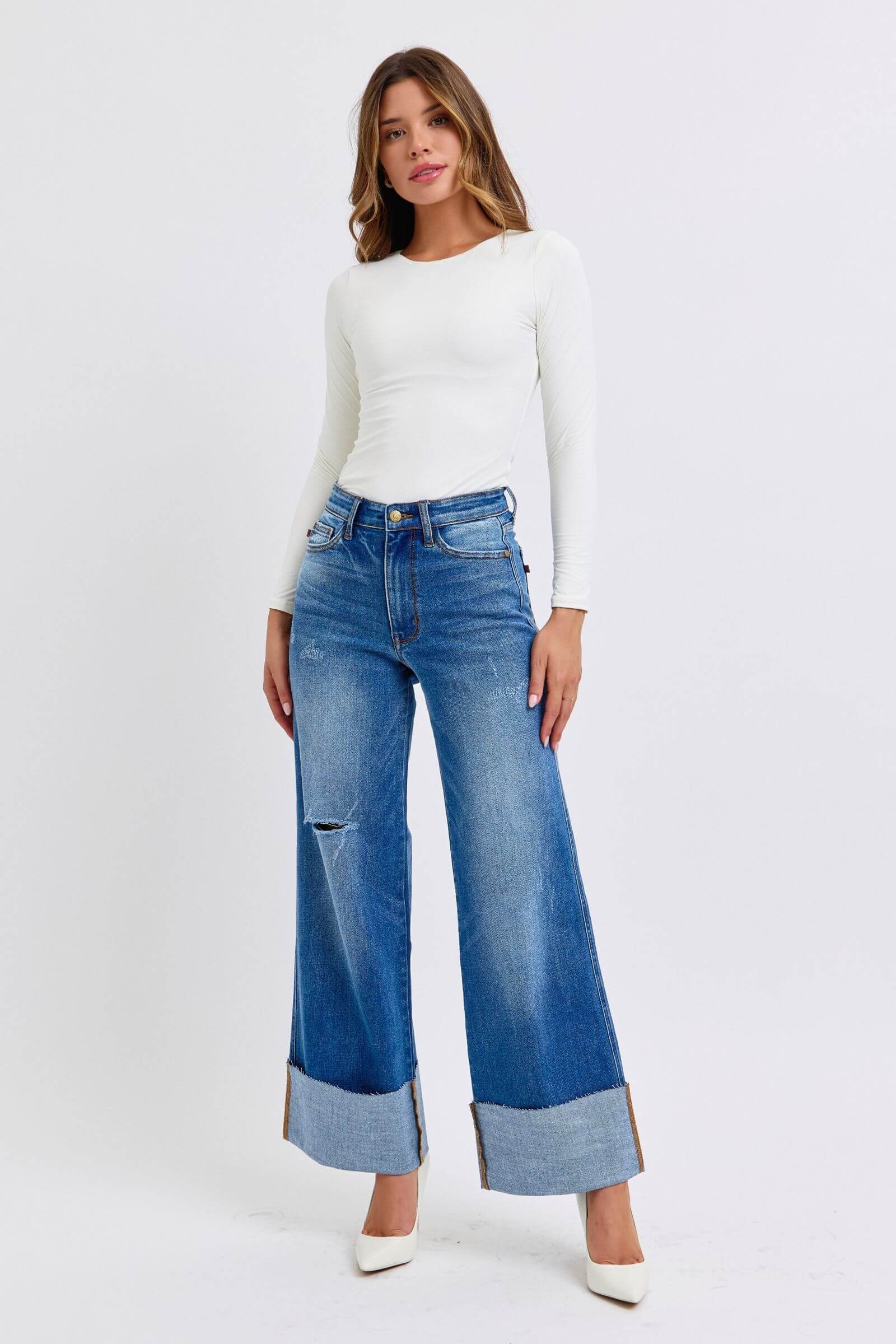 Stylish model wearing Judy Blue distressed high waist wide leg jeans with a fitted white top and heels.