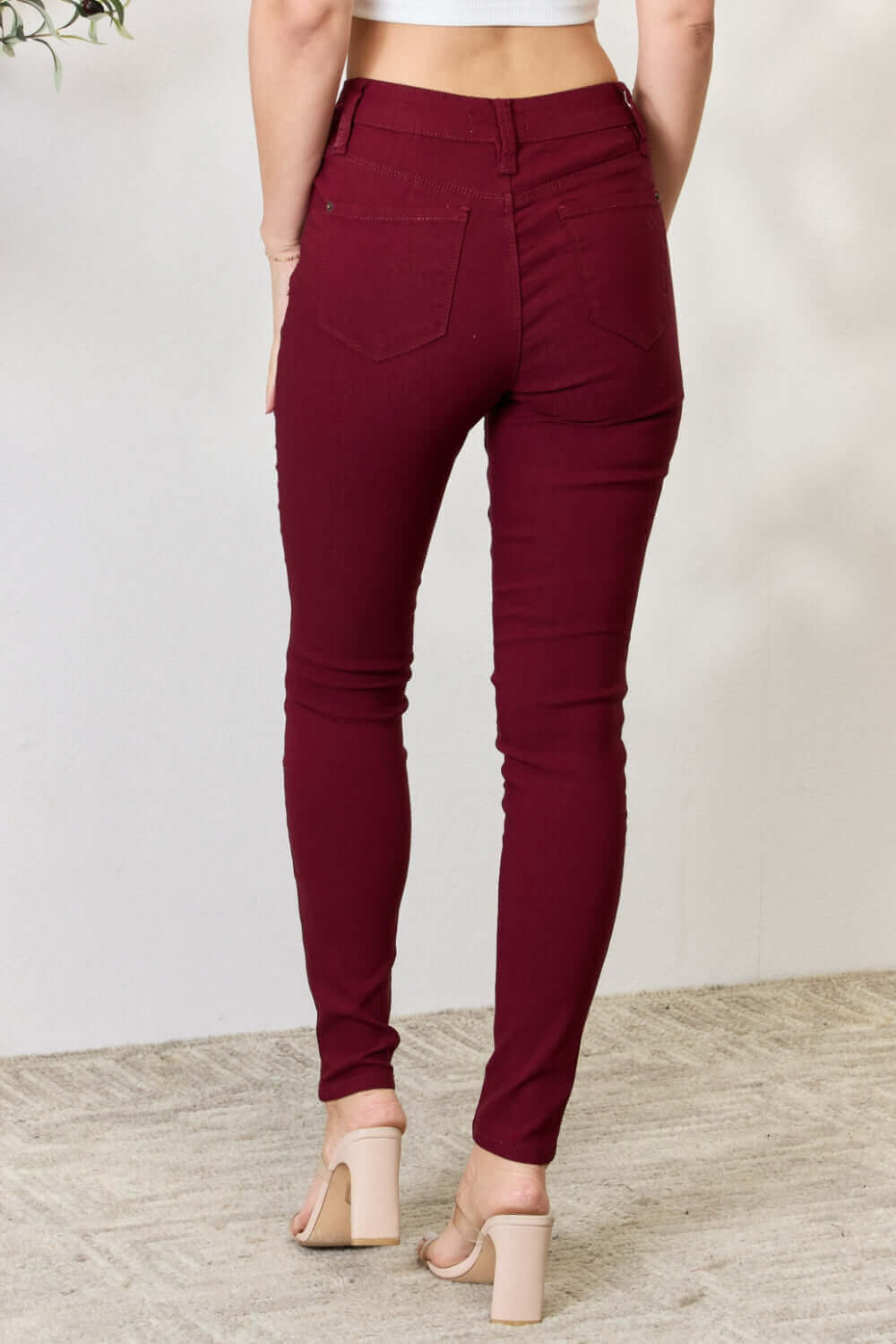 Mid-rise burgundy skinny jeans with stretch from YMI Jeans showcasing back pockets and trendy fit.