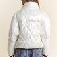 Woman in white quilted mock neck puffer jacket with diamond stitch detail, shown from the back, paired with a blue skirt.