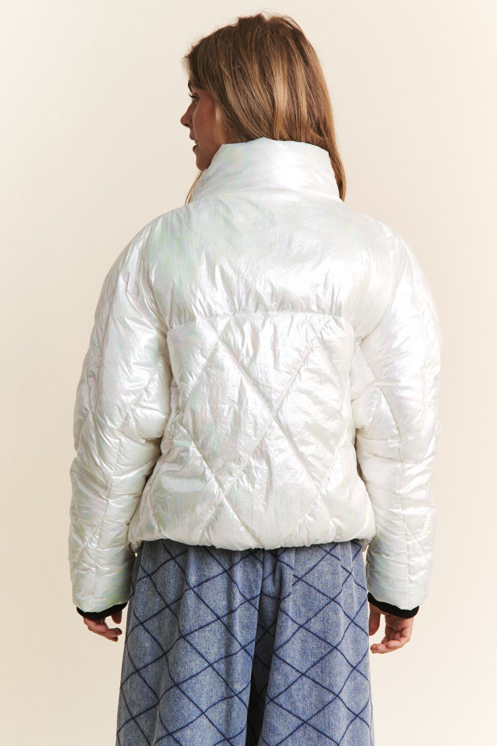 Woman in white quilted mock neck puffer jacket with diamond stitch detail, shown from the back, paired with a blue skirt.