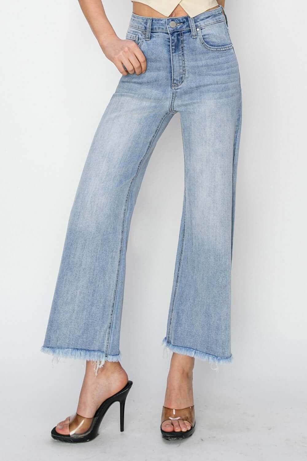 Fashionable high rise crop wide fray hem jeans paired with heels for a chic and edgy style statement.