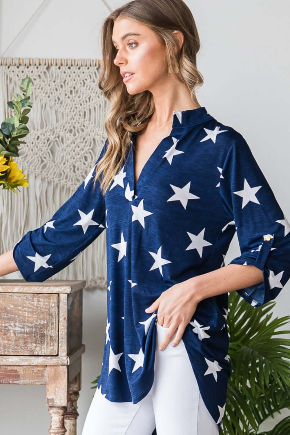 Woman wearing Heimish Full Size Roll-Tab Sleeve Star Print Top with white stars, styled for casual chic look with adjustable sleeve length.