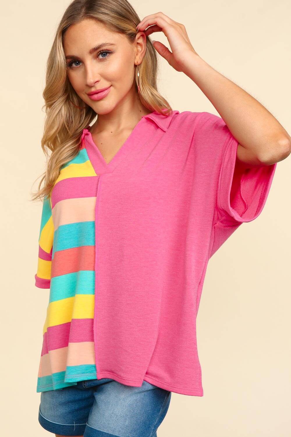 Woman wearing a pink short sleeve half-striped t-shirt with exposed seams and colorful stripes on one side