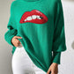 Bella Road Lip Turtleneck Long Sleeve Sweater in green, featuring a bold red lip design, paired with white pants.