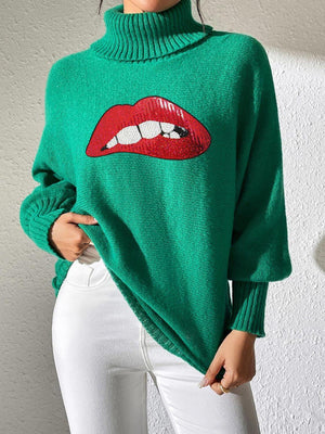 Bella Road Lip Turtleneck Long Sleeve Sweater in green, featuring a bold red lip design, paired with white pants.