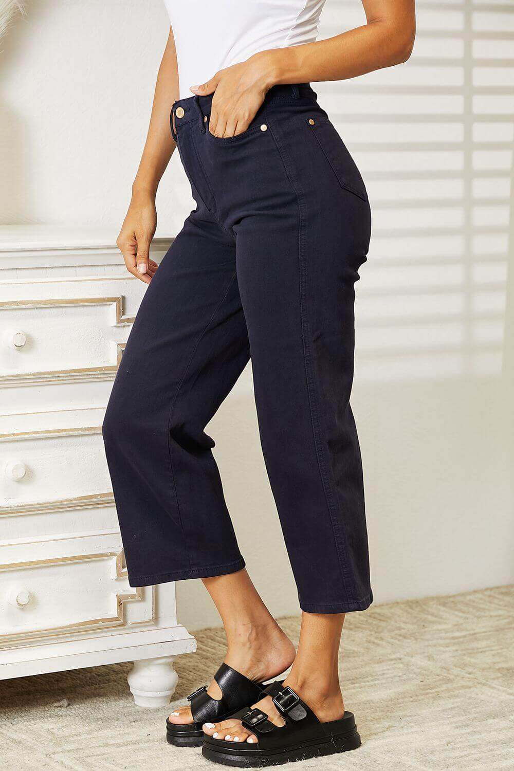 Woman wearing high waist tummy control garment dyed wide cropped Judy Blue Jeans in a stylish setting.