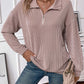 Woman wearing a Striped Half Zip Long Sleeve T-Shirt in beige, paired with blue jeans and holding a beige handbag.