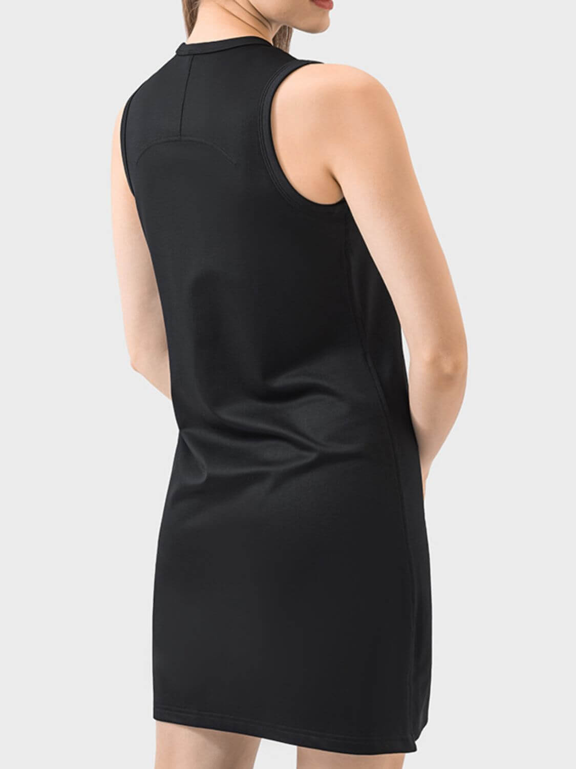 Woman wearing a sleeveless black Millennia dress, showcasing a round neck design perfect for active wear.