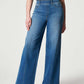 Woman wearing chic wide leg long jeans in solid blue denim with moderate stretch, featuring a high waist and a basic style, ideal for casual wear.