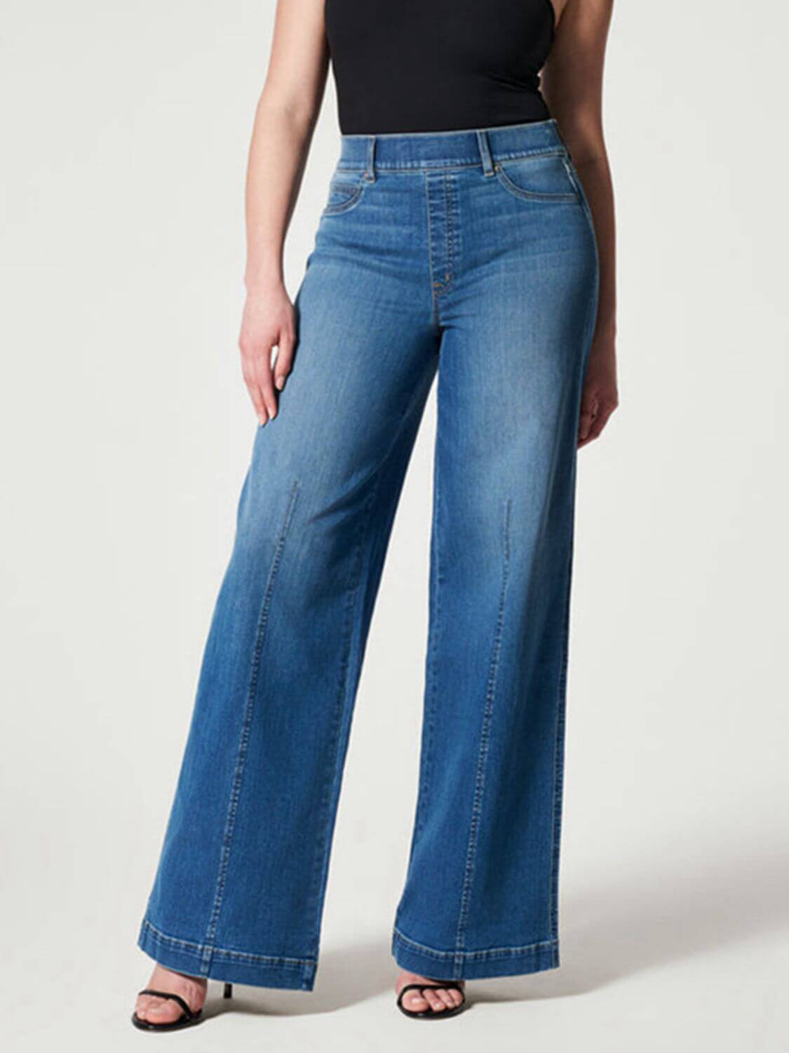 Woman wearing chic wide leg long jeans in solid blue denim with moderate stretch, featuring a high waist and a basic style, ideal for casual wear.