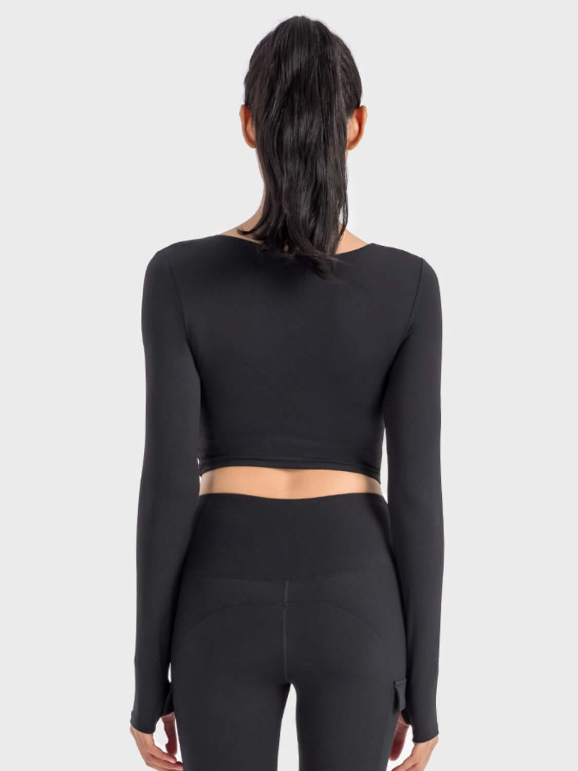 Back view of the Millennia Ruched Cropped Long Sleeve Sports Top in black, showcasing its stylish crop design and fitted look.