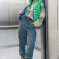 Woman wearing washed drawstring jogger cargo jeans with pockets, paired with a colorful sweater and puffer vest in an elevator.